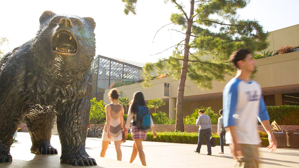 Students pass by The Bruin Statue and John Wooden Center.